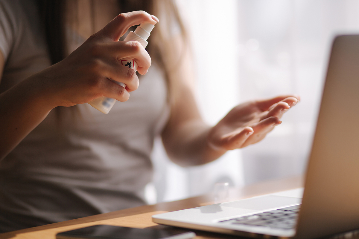 Woman at work using hand sanitizer for COVID workplace protection